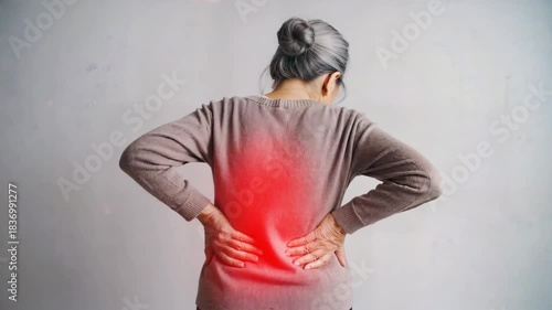 Elderly woman experiencing severe lower back pain and discomfort with visible inflammation highlighted by a red glowing spot on her spine