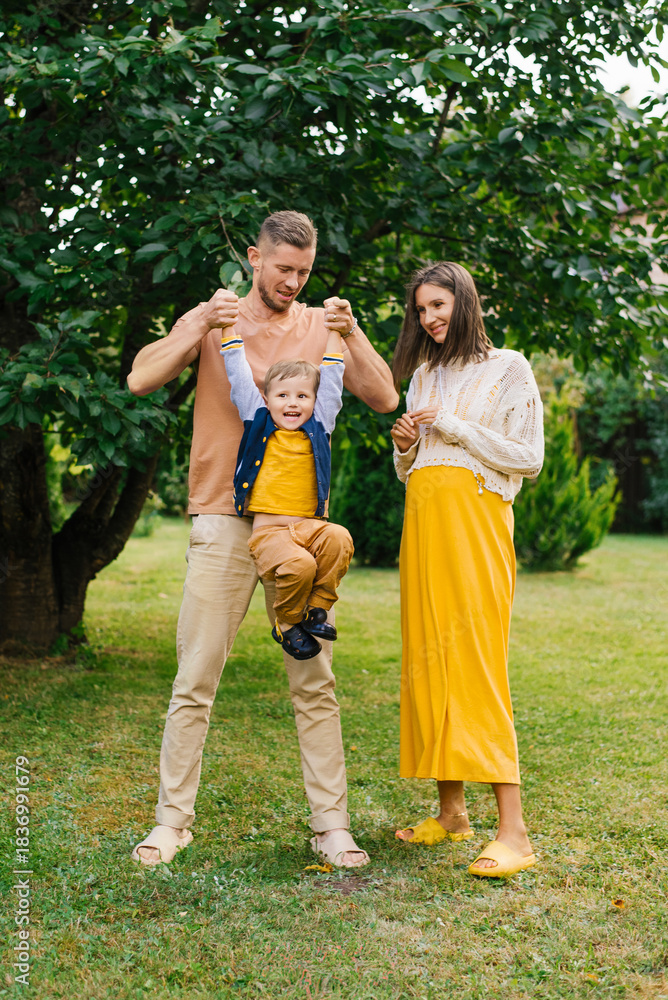 Fototapeta premium Father Lifting Son While Pregnant Mother Watches