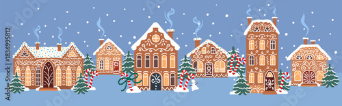Cozy gingerbread town with decorated cookie houses, snowy winter trees and falling snow on a blue night background. Cute bakery style landscape for holiday designs and greeting cards.