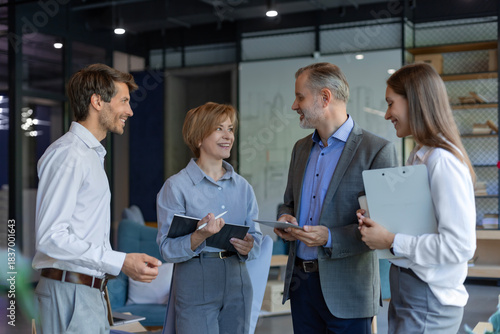Four business people discussing work together using a tablet in a modern office