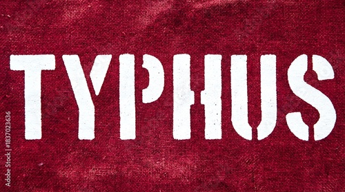 Stark stencil warning TYPHUS boldly stamped across rich textured crimson fabric background