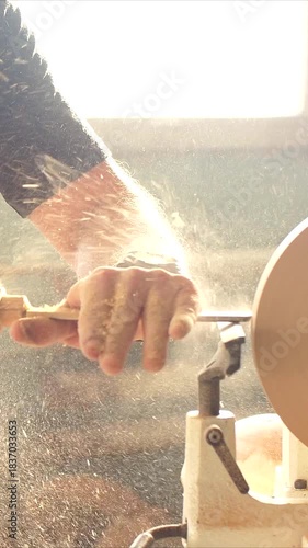 Wood crafting scene, Lathe work captured with flying shavings and sunlight. Craftsman working on wood surface surrounded by lively dust particles. Woodworking in progress. Vertical video