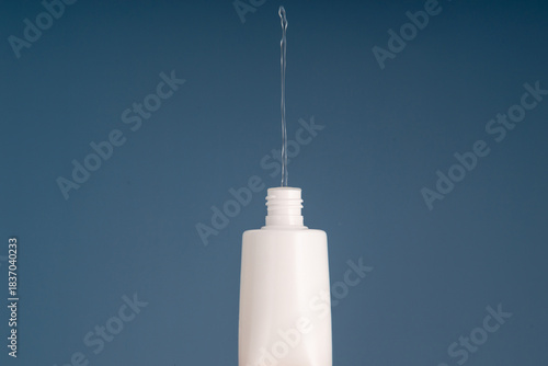 Flow of clear liquid from cosmetic bottle.