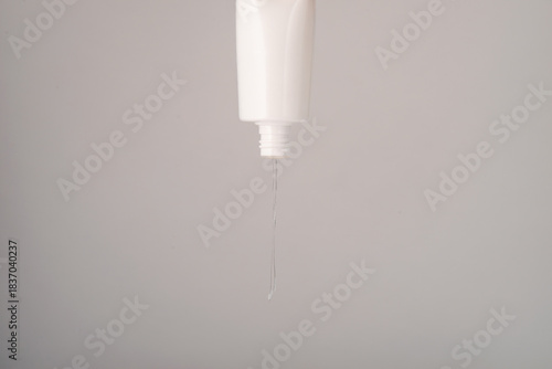 Flow of clear liquid from cosmetic bottle.