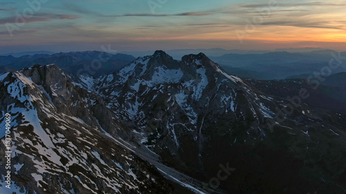 Rocky snow mountains at sunset aerial