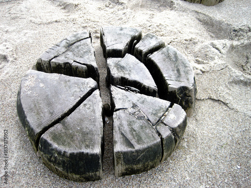 Aufsicht auf eine tief im Sand steckenden Buhne aus verwittertem  Holz