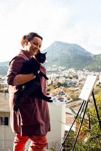 mature brunette woman painter outside drawing with her black cat, lifestyle people concept