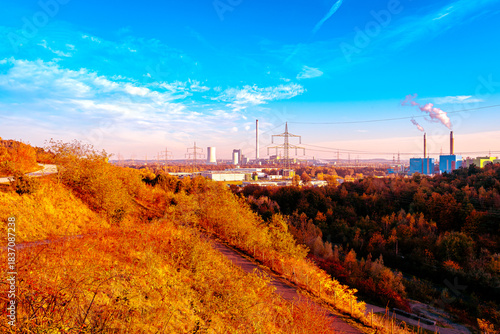 Ein leuchtend blauer Himmel spannt sich über eine Landschaft, in der die Natur in den feurigsten Rottönen des Herbstes brennt. Vom Hügel aus gesehen bildet der gold-orangefarbene Hang einen dramatisch