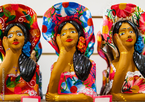 Row of traditional ceramic dolls painted in bright colors depicting the bust of afro brazilian women looking out the window, Brazil