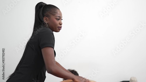 Professional african american masseuse performing back massage