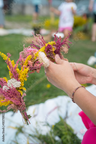 Female hands making traditional flower crown with wild flowers for midsummer celebration or bridal party