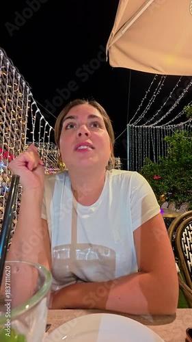 Young Woman Contemplating Under Festive Lights at Night