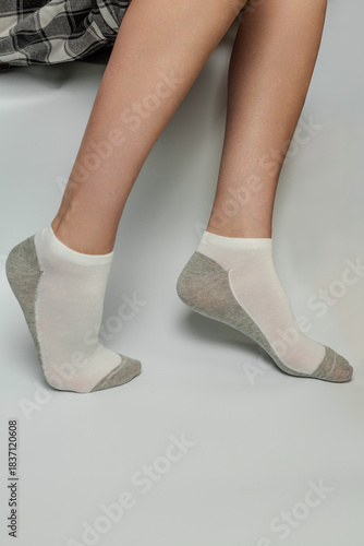 Legs and feet in comfortable white and grey ankle socks on a plain background isolated