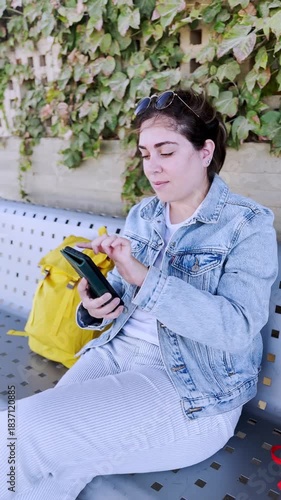 Young Woman Typing on Her Smartphone at a Train Station