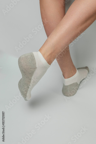 Legs and feet in comfortable white and grey ankle socks on a plain background isolated