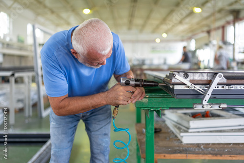 A worker in an aluminum and PVC factory works on profiles.