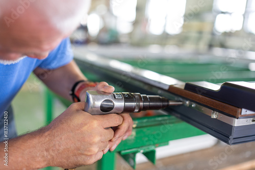A worker in an aluminum and PVC factory works on profiles.