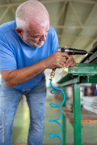 A worker in an aluminum and PVC factory works on profiles.