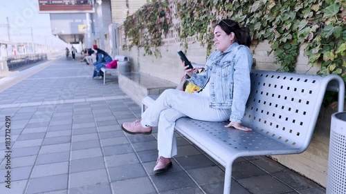 A Woman Reacting Happily to Her Phone at a Train Station