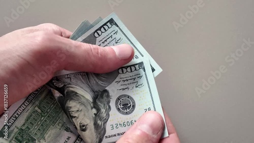 Close-up of male hands counting a stack of us one-hundred-dollar bills