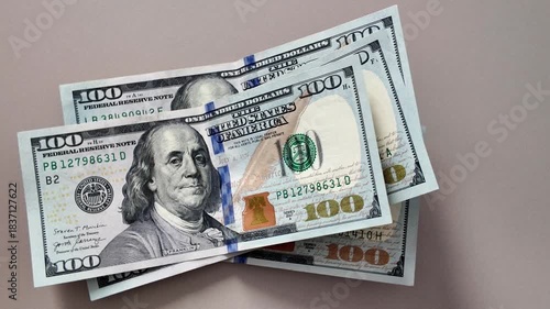 Close-up of hundred dollar bills falling one after another onto the table surface