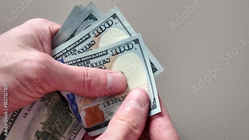 Close-up view of a person's hands counting a stack of united states one hundred dollar bills. Financial concept of wealth, salary, and payment