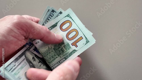Close-up of hands counting a stack of hundred dollar bills