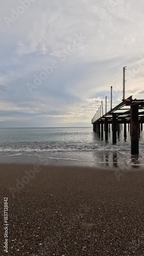 atmospheric view of an old dock with calm sea and clouds