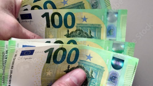 Close-up of a man's hands counting a stack of one hundred euro banknotes