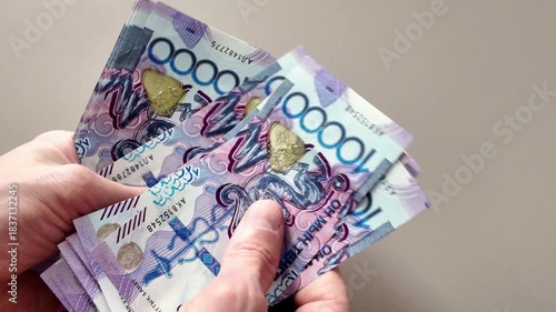 Close-up of a man's hands counting a stack of ten thousand Kazakhstani tenge banknotes