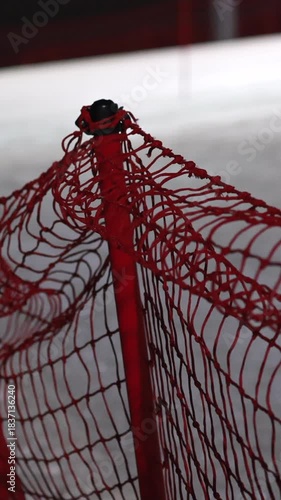 Close Up Of A Red Safety Net On An Indoor Ski Slope, Gently Swaying In A Light Breeze Or Air Current. Focus On Netting Texture And Support Poles. Winter Sports Detail. Vertical