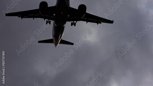 Airplane flying through dark clouds, camera pans upward capturing flight dynamics. slow motion