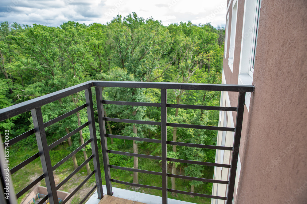 Obraz premium Modern balcony with metal railing overlooking green forest.