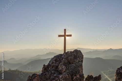 Silhouettes of crucifix symbol on top mountain with bright sunbeam on the colorful sunset sky background