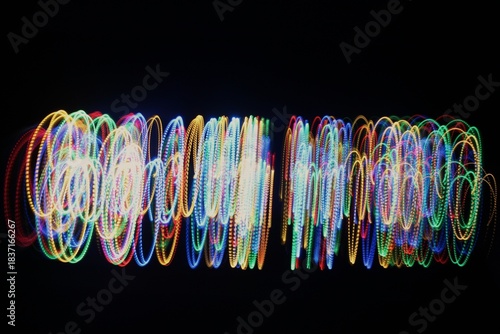 Long exposure light painting photography. Swirls of multicolor light in parallel lines against a black background
