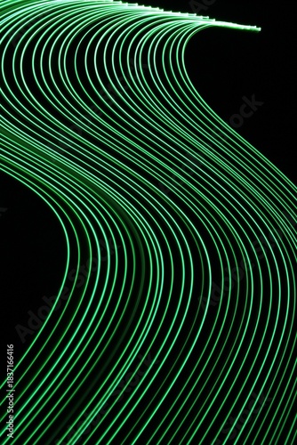 Long exposure light painting photography. Swirls of green light in parallel lines against a black background