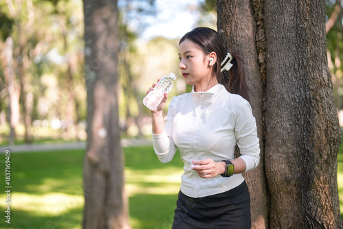 Wallpaper Mural Fit young adult Asian woman rehydrates water bottle outdoor fitness activity vibrant park promoting healthy lifestyle physical wellness mindful exercise routine Torontodigital.ca