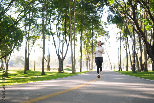Wallpaper Mural Asian adult woman jogs outdoor park path wellness physical activity natural environment healthy lifestyle exercise training Torontodigital.ca