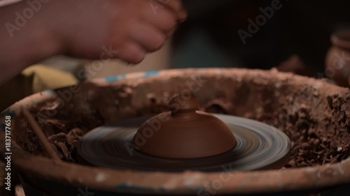 Potter trimming clay pot lid on pottery wheel close-up
