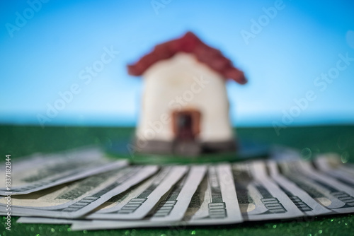 A house leaning against $100 bills, studio photograph. Concept.
