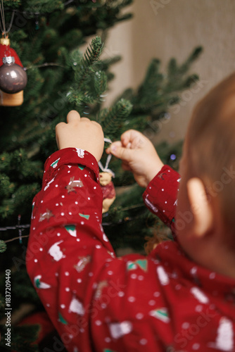 Kids’ hands decorating a holiday tree with sparkling ornaments, cozy winter atmosphere.