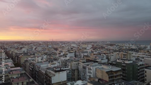 Bari at dusk with a panoramic view of the historic center, bustling port, and calm Adriatic Sea under dramatic clouds and soft sunset light.a