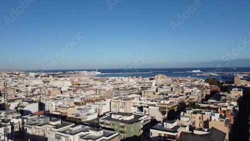 A vibrant aerial panorama of Bari, Italy, capturing the golden-hued Old Town and port alongside the modern city grid, stretching out to the deep blue Adriatic horizon.a