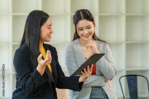 Portrait of two young businesswomen having a meeting or presentation and seminar standing in the office. Portrait of a young businesswoman talking.