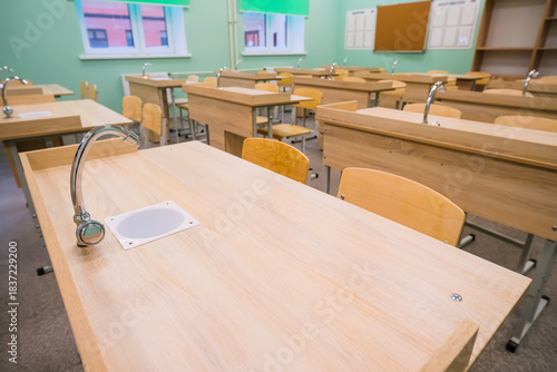A modern classroom in a school or educational institution. A blackboard with several chalk writing panels and an interactive digital panel.