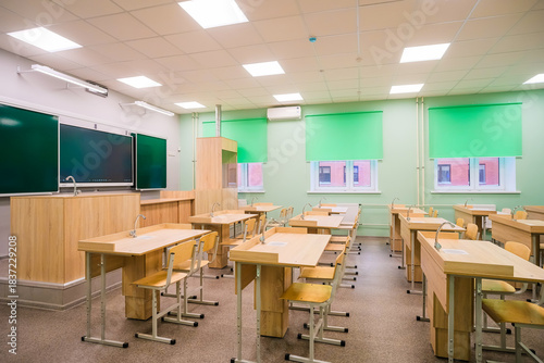 A modern classroom in a school or educational institution. A blackboard with several chalk writing panels and an interactive digital panel.