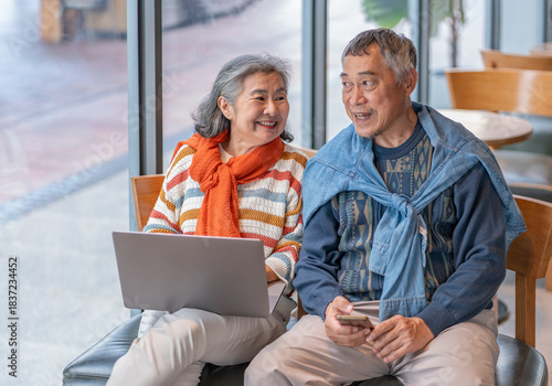 elderly people with modern lifestyle,bonding asian senior couple sitting in coffee shop,old man using smartphone surfing internet online and a woman using laptop to work
