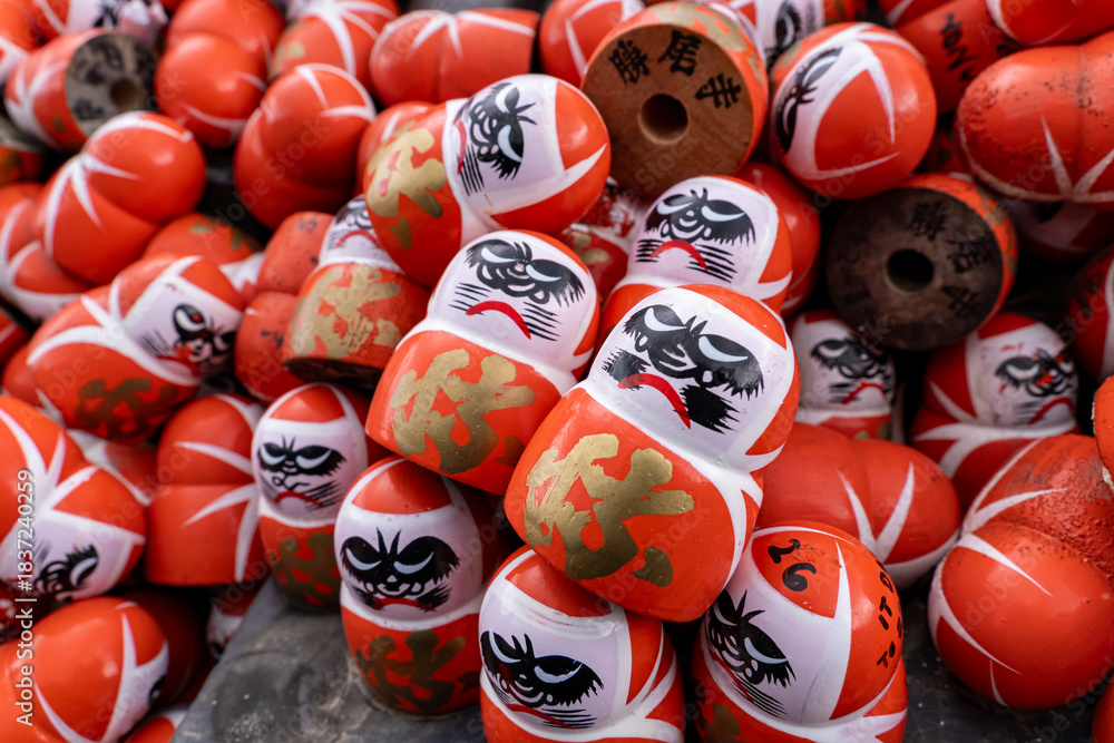 Naklejka premium Daruma dolls display at a market during festival in Japan with vibrant colors and intricate designs on each figure