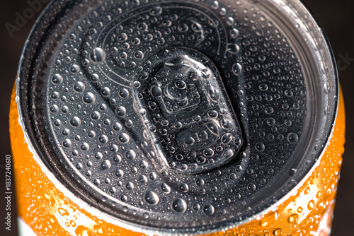 The top of an orange tin can of cold drink covered in water droplets