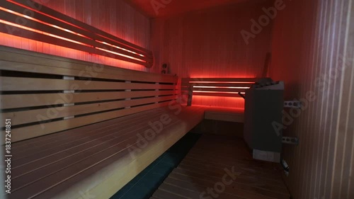 Warm, inviting sauna interior with wooden benches and walls bathed in soft, ambient red light. A serene space designed for relaxation and rejuvenation